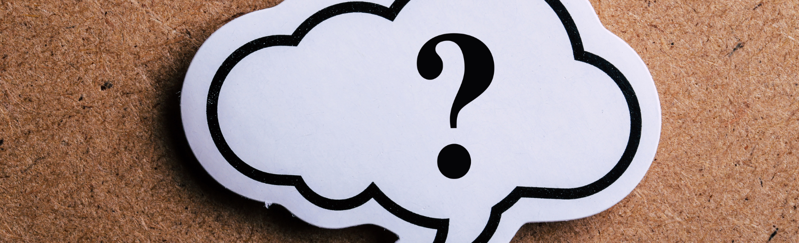 Image of a question mark on a piece of paper. The paper is shaped like a thought bubble and overlaps a bulletin board background.