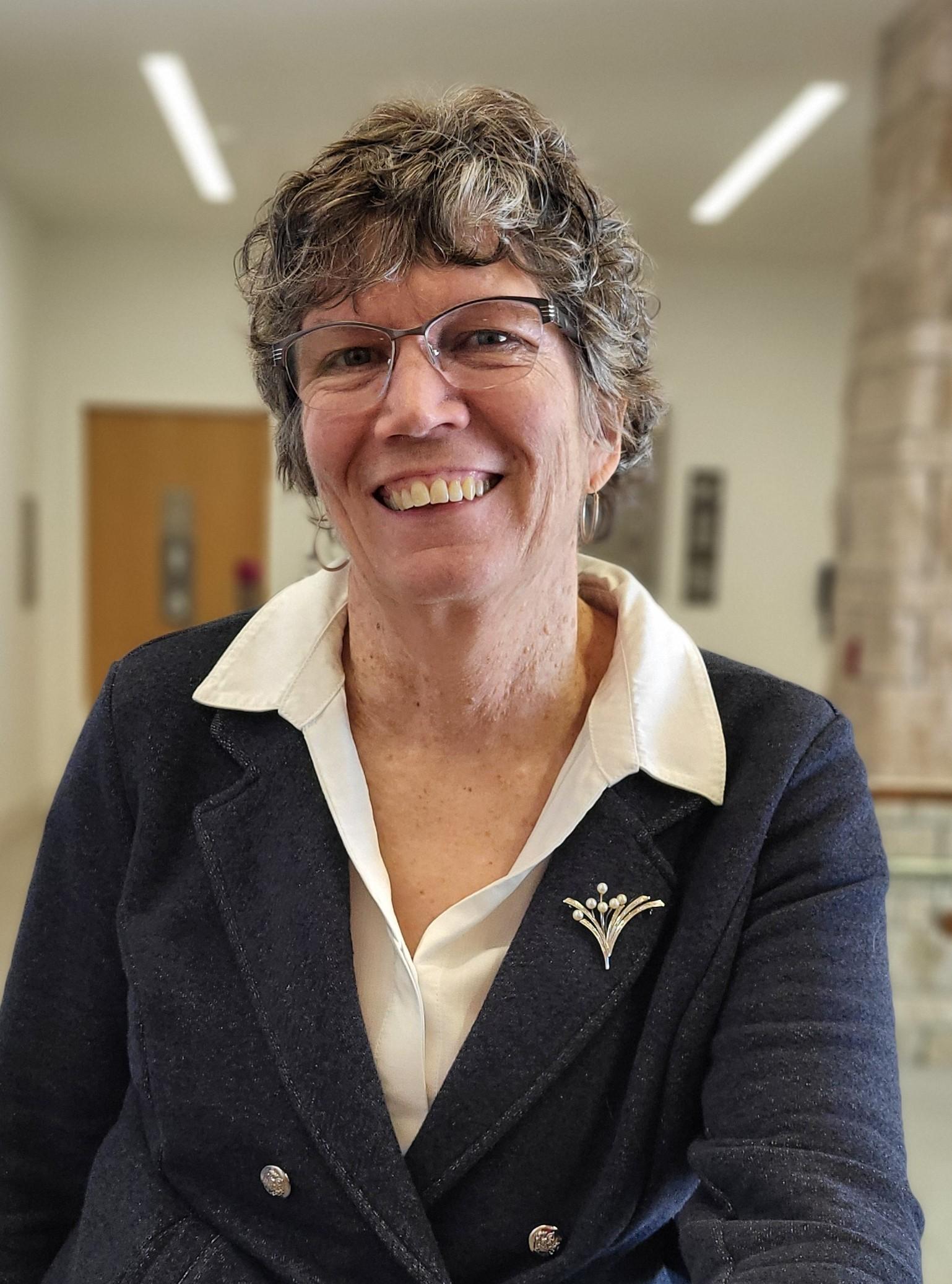 Isabel smiles at the camera in a blue blazer