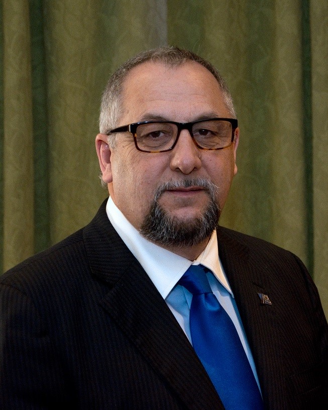 Headshot of Board Member, Rick Champagne in a suit and tie, and wearing glasses