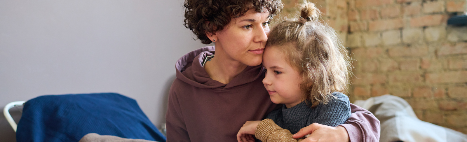 Young girl with teddy bear getting side hug from a teen or young adult