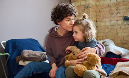 Young girl with teddy bear getting side hug from a teen or young adult