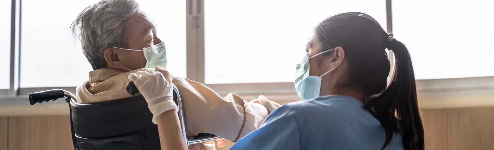 Image of a long-term care resident and staff member interacting and wearing face coverings
