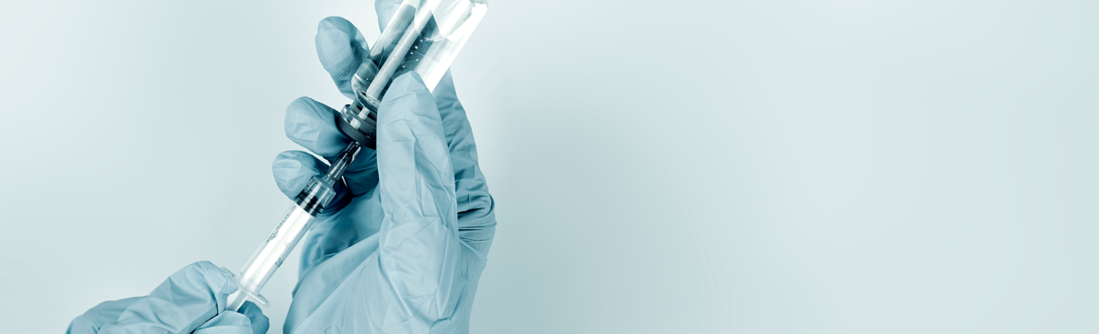 Image of hands wearing latex gloves, filling a syringe with vaccine