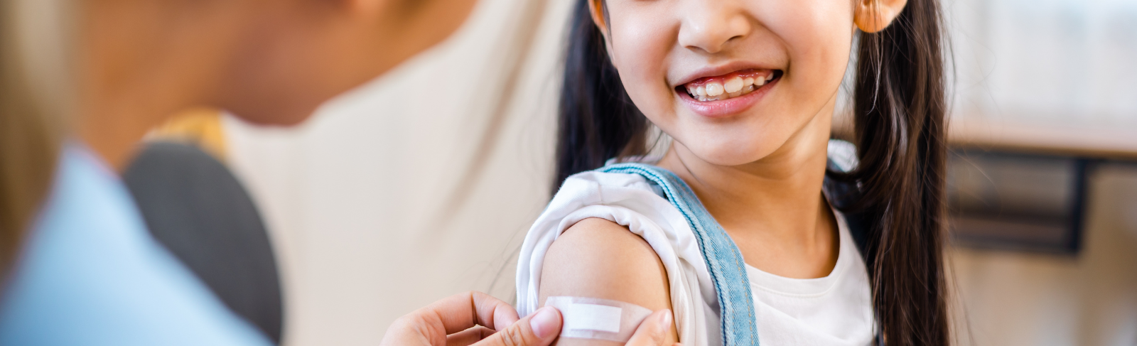 Image of a child's smile and a bandage being placed on their upper arm