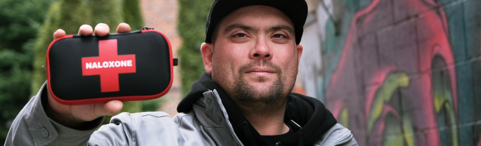Image of someone holding a naloxone kit at eye level, toward camera