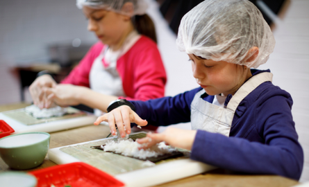 Child wearing apron and hair net, making food from scratch