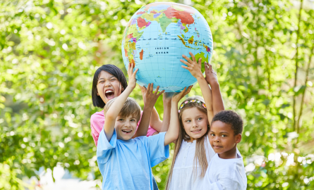 Image of four children outdoors, holding up a globe