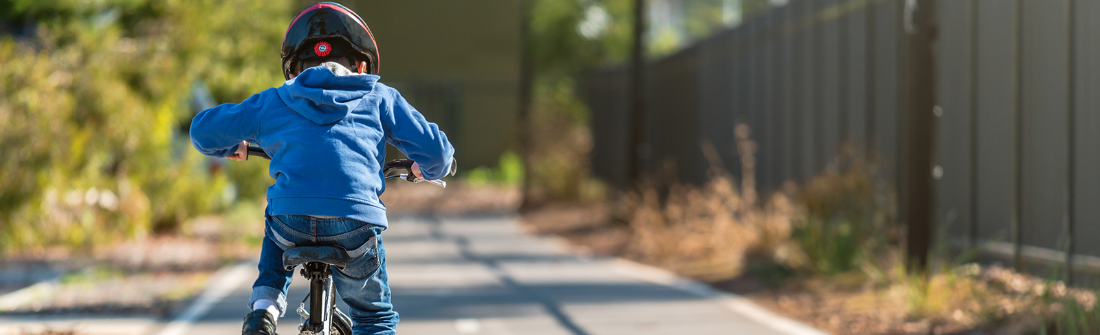 Child biking away with a helmet on.
