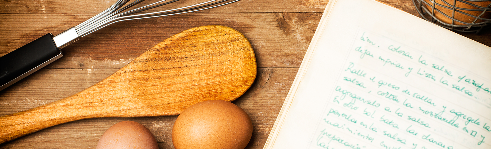 Cook book with an egg, whisk and wooden spoon.