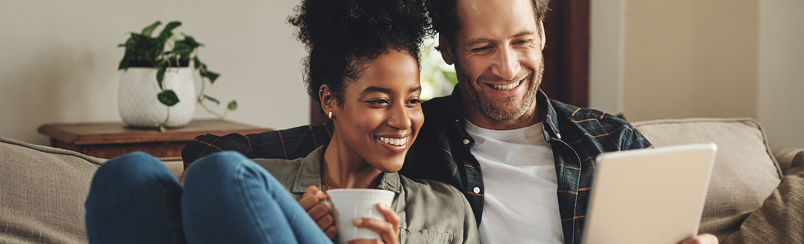 Couple sitting on a couch looking at a tablet