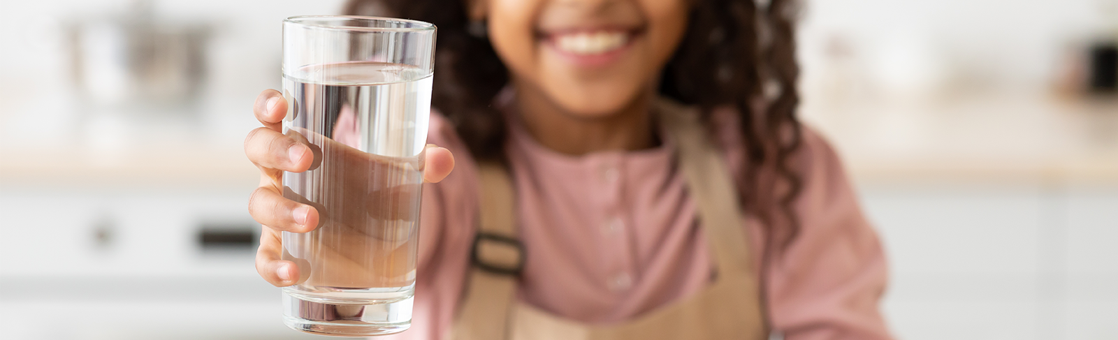 Child holding a glass of water, Child out of focus glass of water in focus.