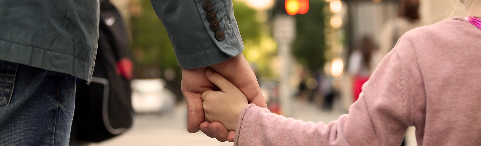 Father in blue coat holding daughter in pink sweater's hand