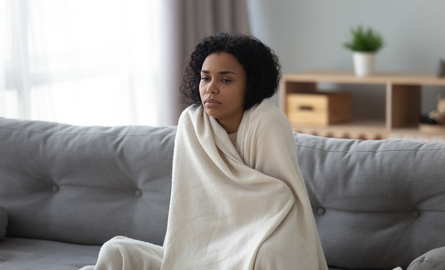 Person wrapped in blanket, looking unwell