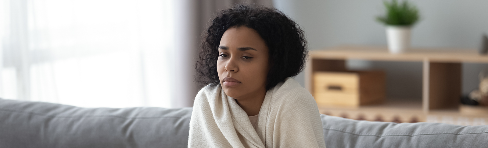Women sitting with blanket wrapped around her.
