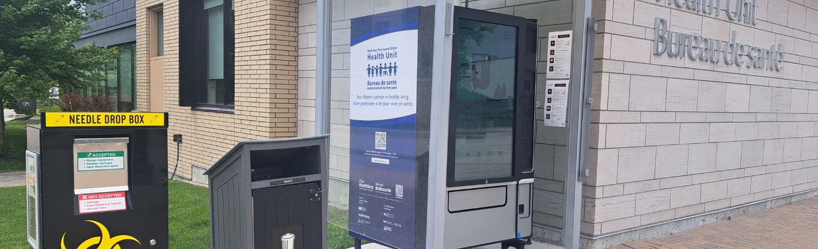 Image of a community sharps bin, a waste bin and a Healthbox outside the Health Unit