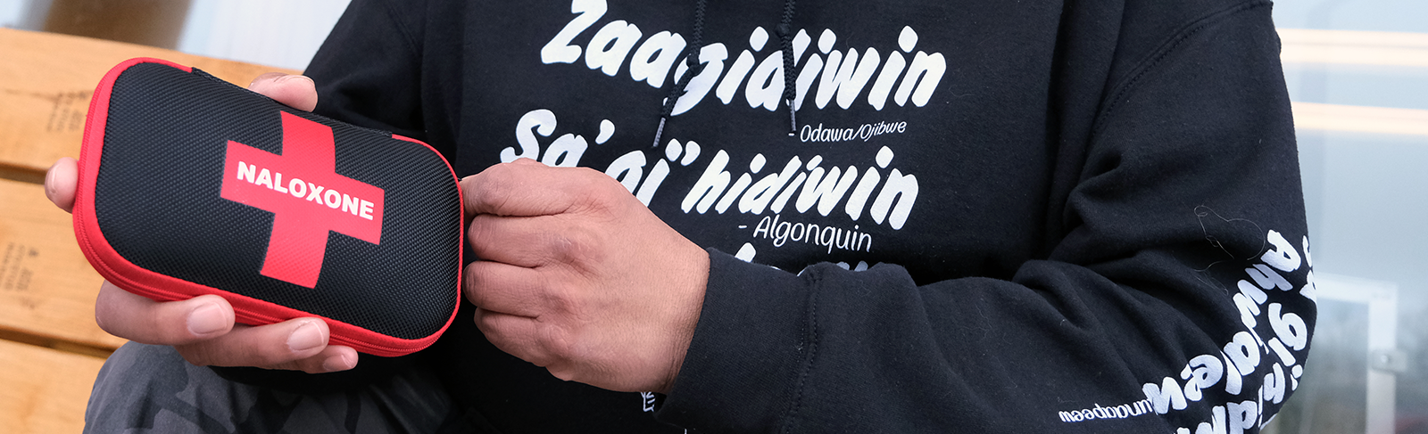 Someone in a black sweater holding a naloxone kit
