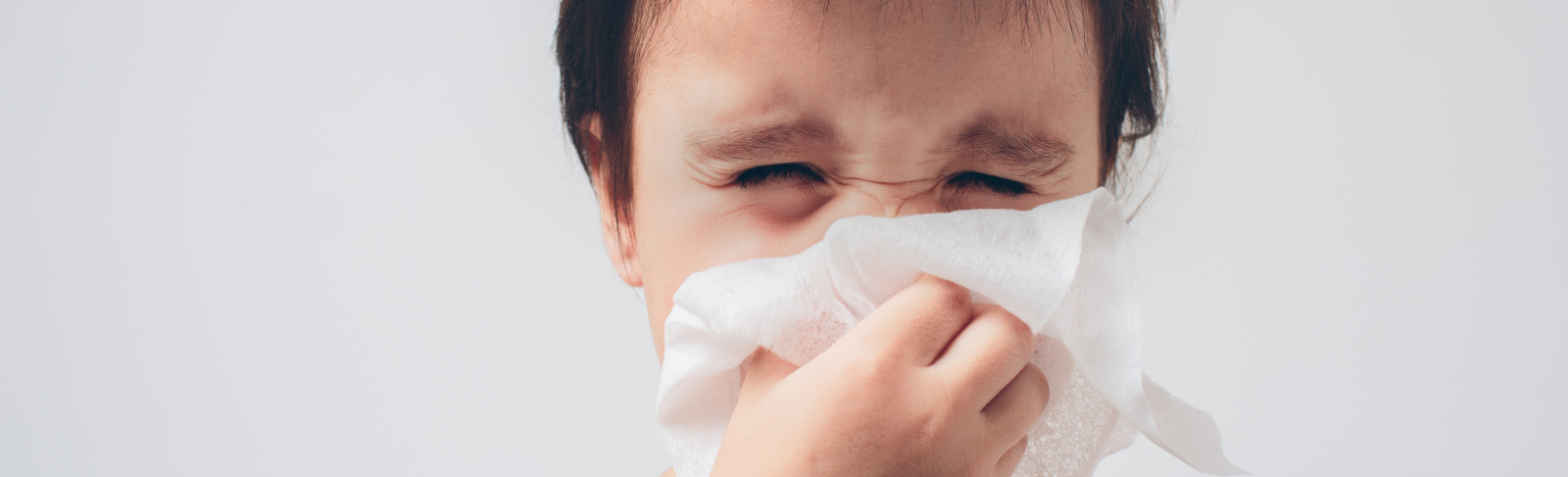 Toddler sneezing into tissue