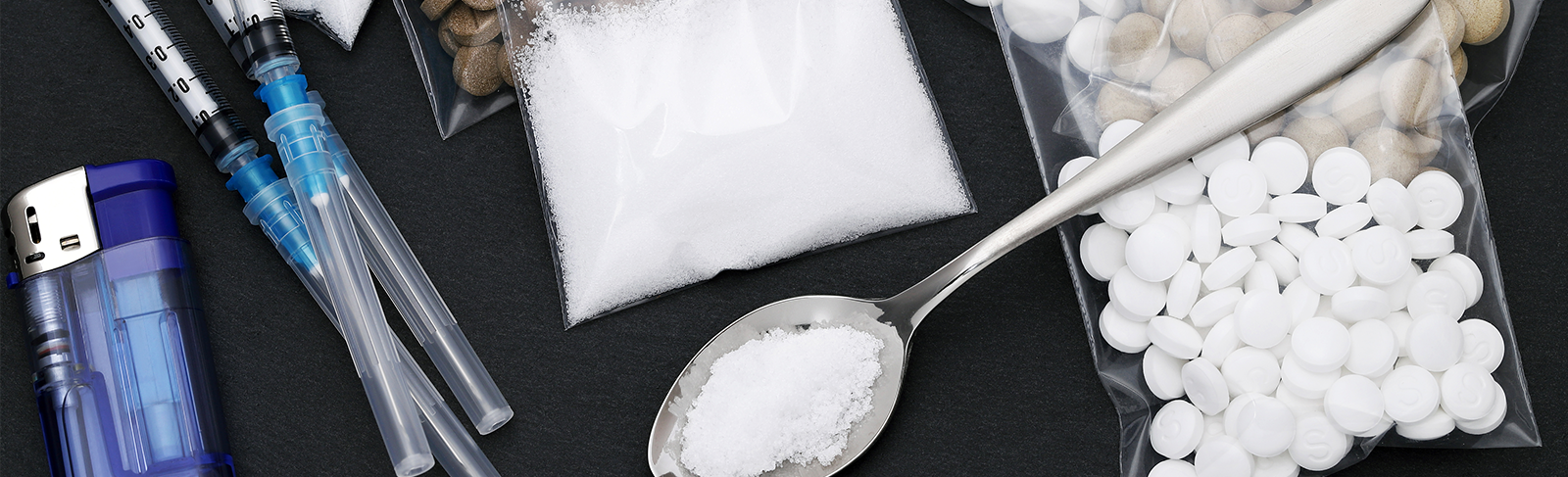 Needles, spoon with substances on it and pills in bags