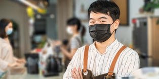 A business owner wearing a face covering