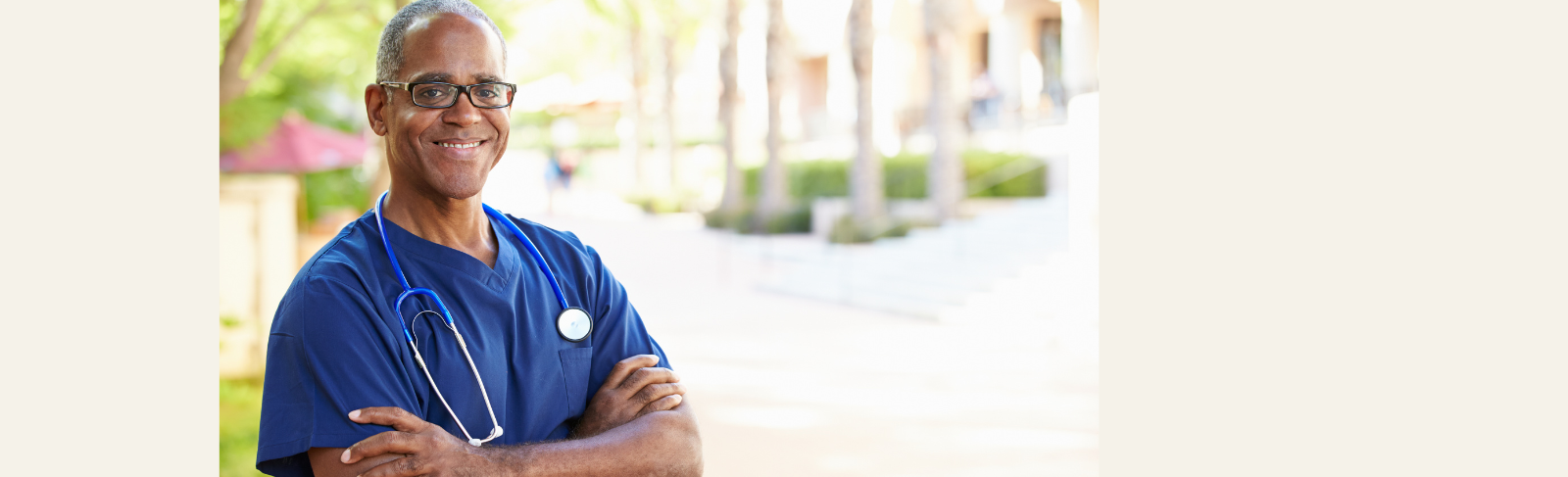 Image of a person standing outside, wearing scrubs, a stethoscope around their neck