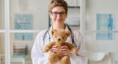 A pediatrician holding a teddy bear