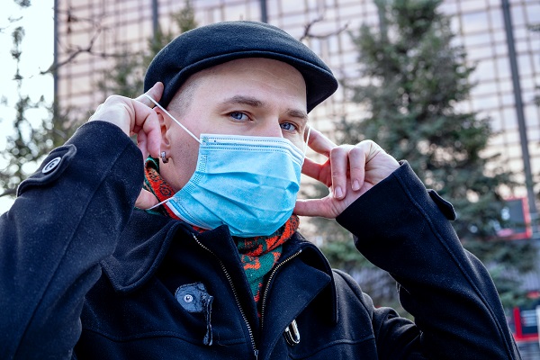 Image d'une personne à l'extérieur en tenue d'hiver, mettant un masque de protection.