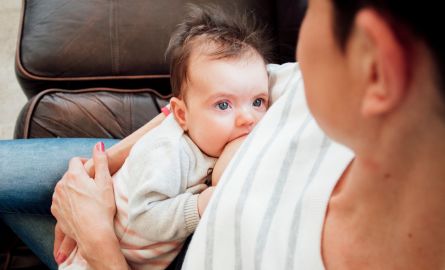 Baby breastfeeding and making eye contact with feeding parent