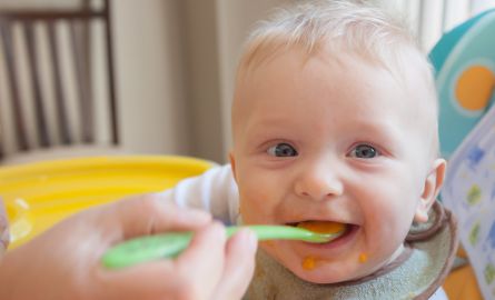 Baby being fed with a green spoon