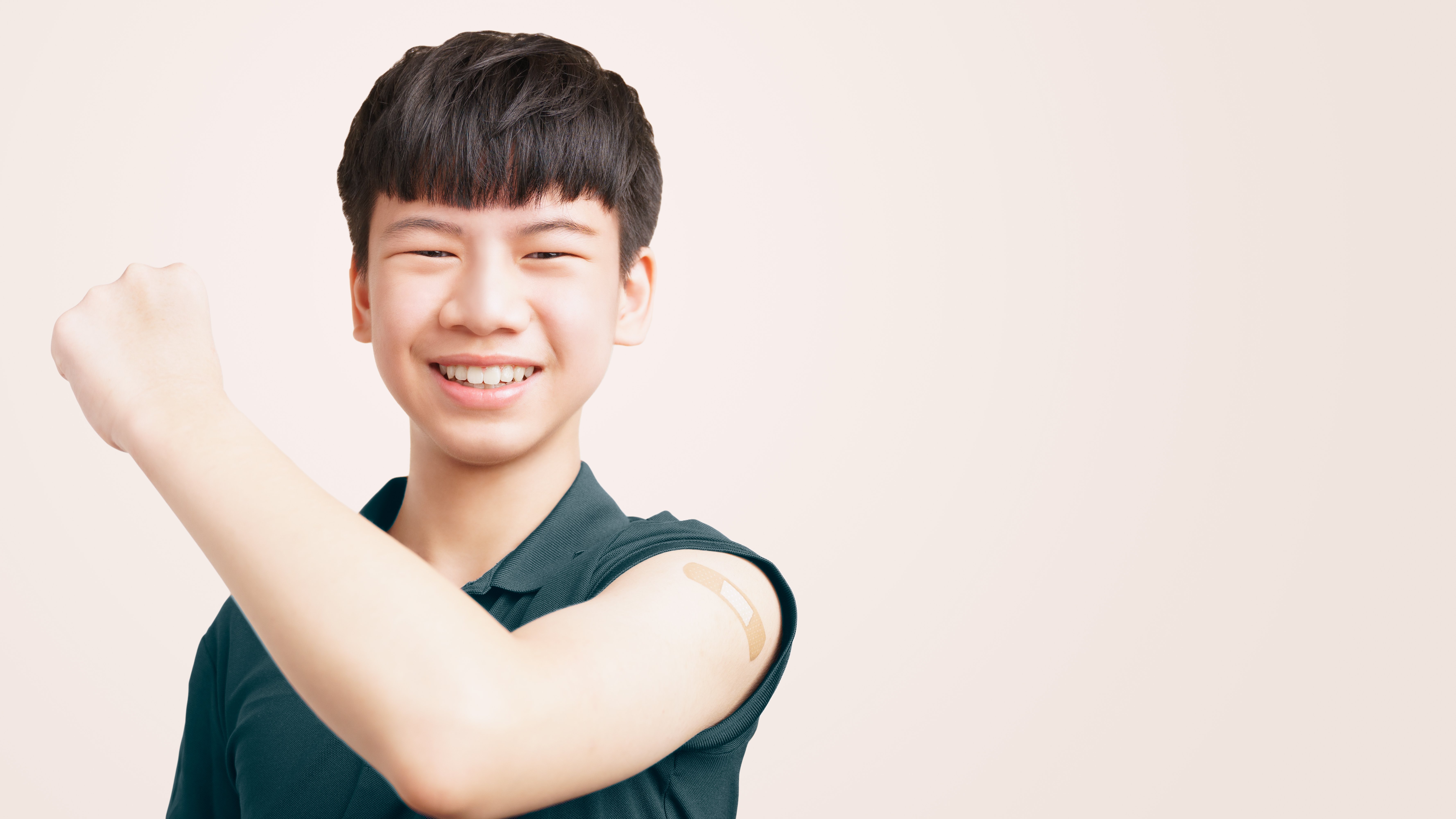 Boy holding his left arm up showing his vaccine spot