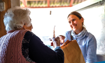 Senior receiving a delivery from a volunteer at their door