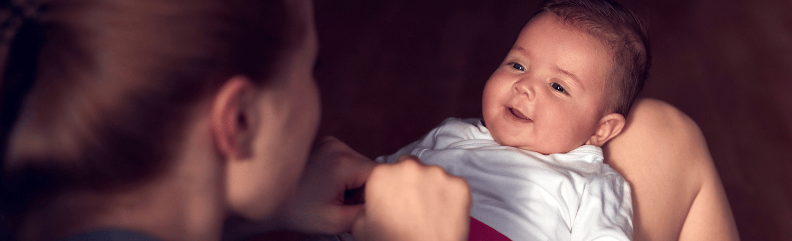 Adult woman looking down at baby on her lap who is looking back