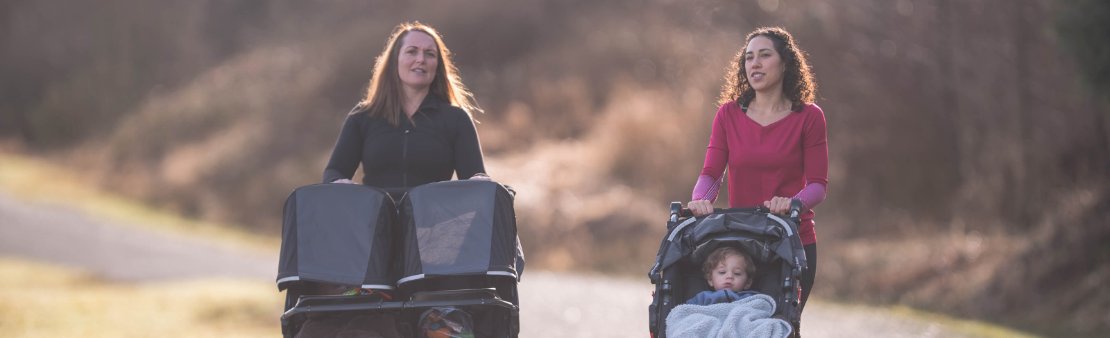 Two people out for a walk with babies in strollers