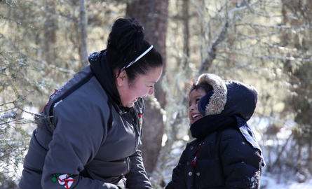 Indigenous child and young adult playing outdoors together in winter