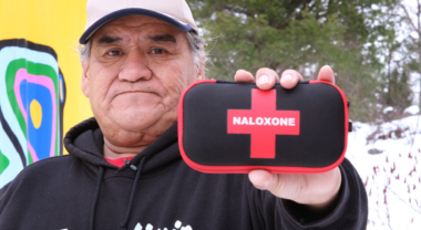Image of a person holding up a naloxone kit