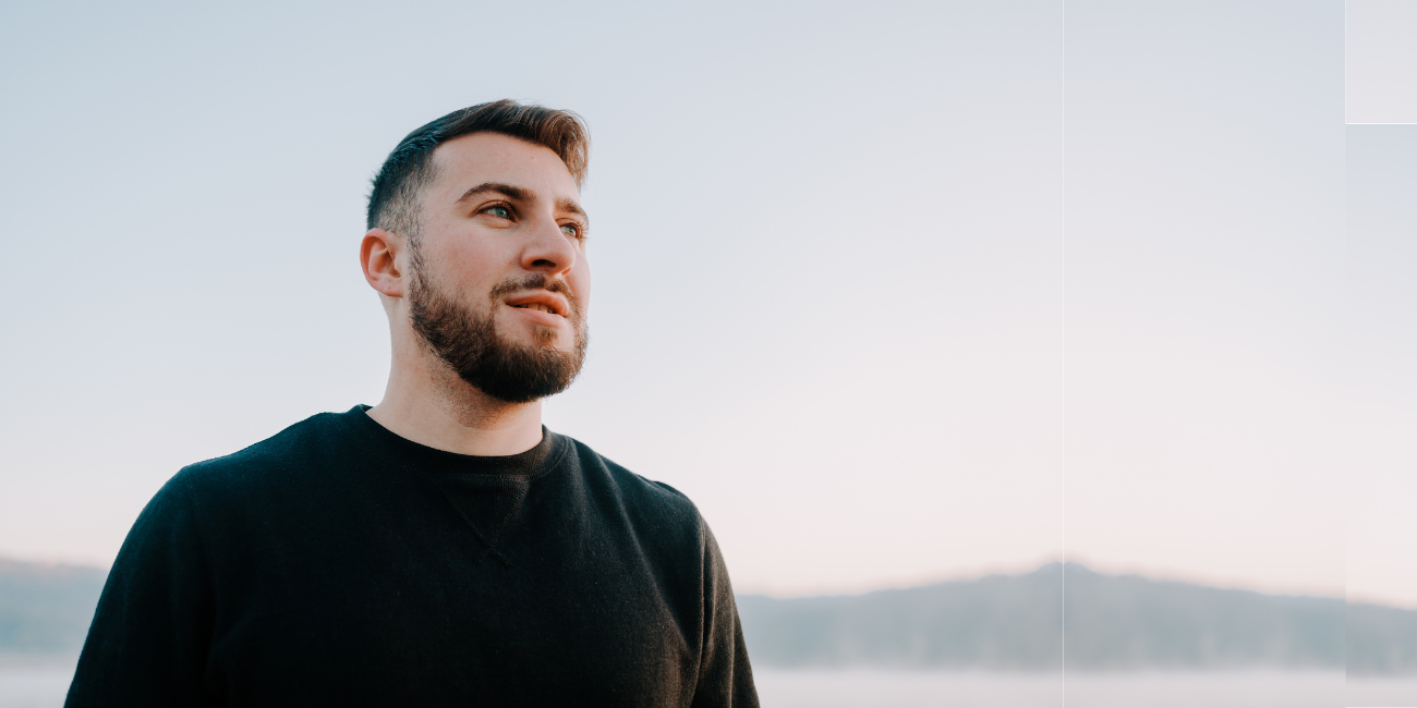 Close-up image of a male-presenting individual outside on cloudy day