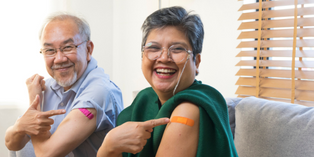 Image of two people smiling and pointing to a band-aid on their upper arms