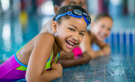 Child in pool wearing bathing suit and goggles