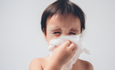 Toddler sneezing into tissue