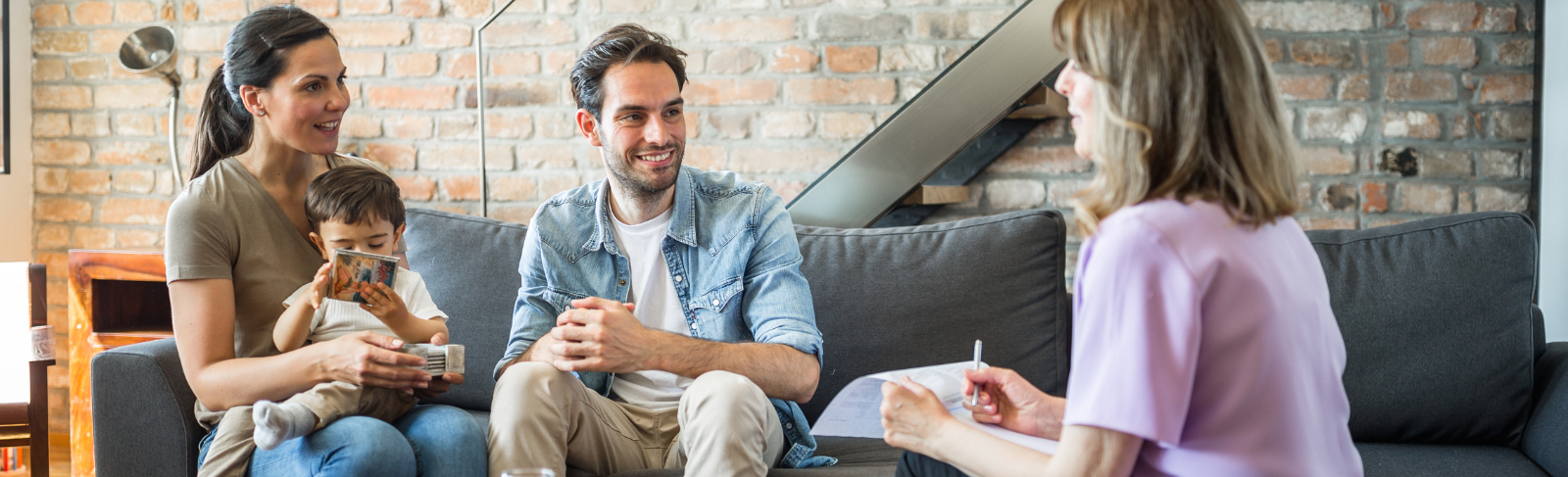 Young couple with toddler listening to professional adult on home couch
