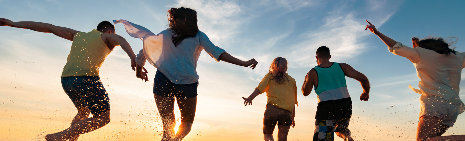 Silhouette image of teens running with enthusiasm into the sunset