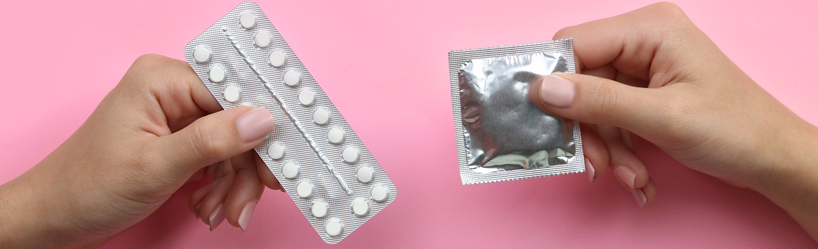 Condom and the pill on a pink background