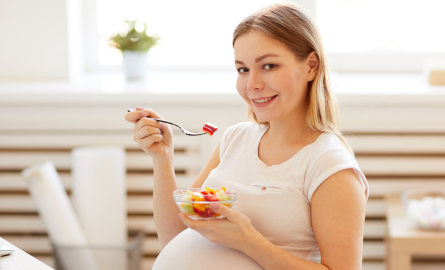 Pregnant individual eating fruit salad