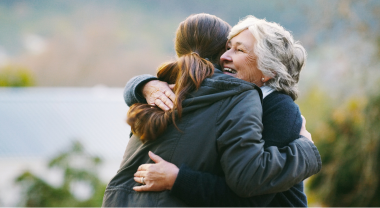 Older woman being hugged by a younger woman in an outdoor setting