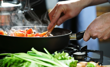 Image of hands cooking food in a pan on stove
