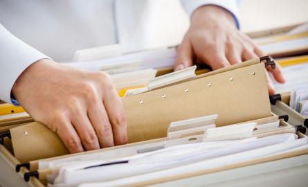 Hand pulling a folder out of a drawer of file folders