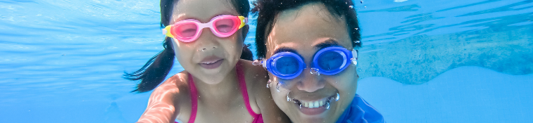 Adult and child under water, wearing goggles