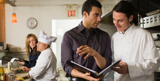 Image of inspectors and chefs discussing inspection in a restaurant kitchen