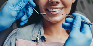 Close up image of a smiling mouth being checked by dentist