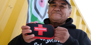 Image of a person holding a naloxone kit