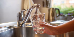 Filling a cup of water at kitchen sink